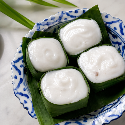 Custard tarts wrapped in green leaves on a blue and white ceramic dish.
