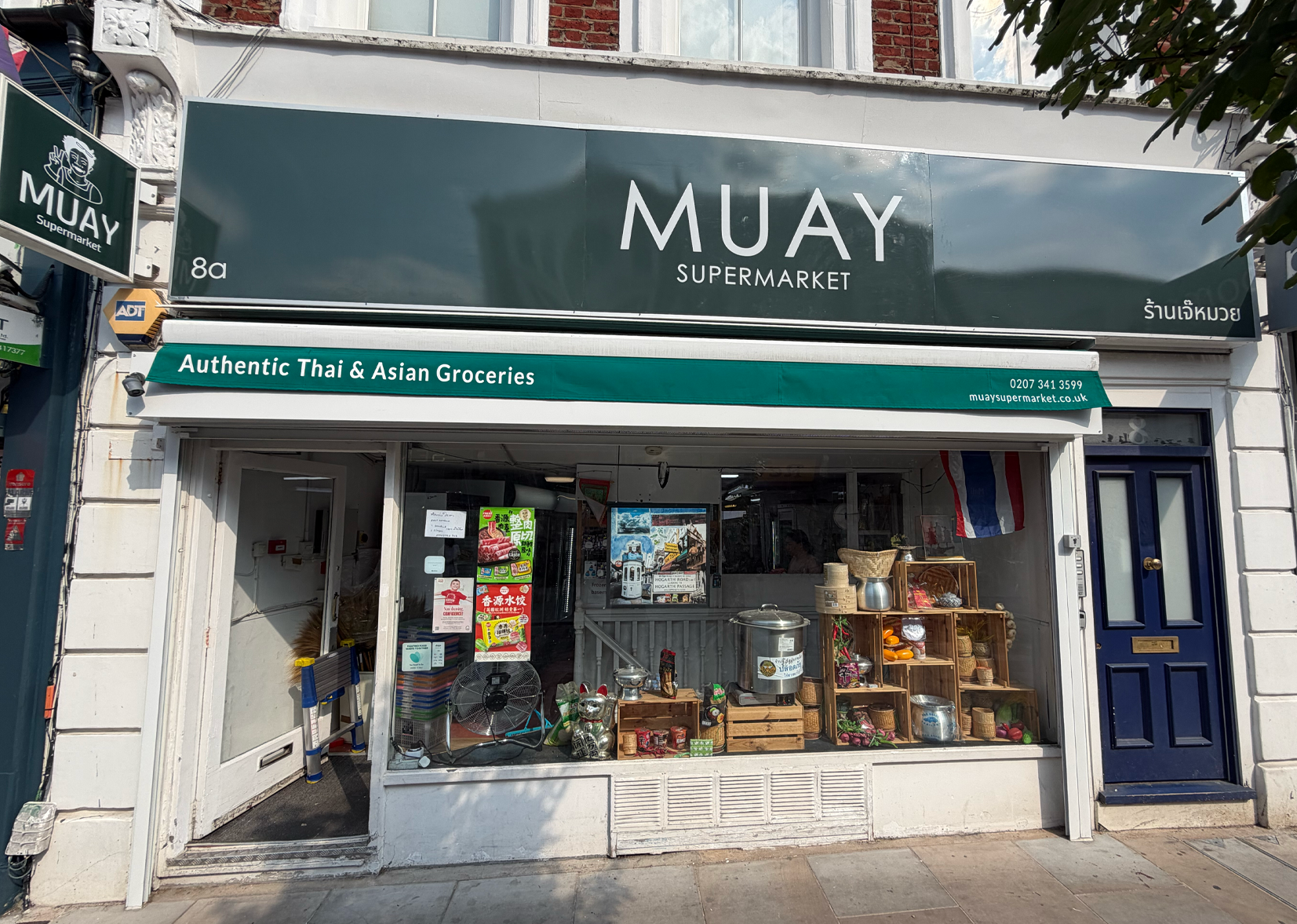 MUAY Supermarket storefront with green and white sign on a city street