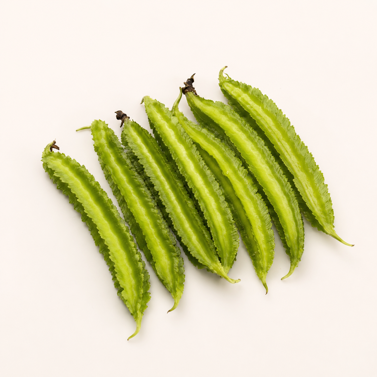 Six winged beans arranged diagonally on a plain off-white background.