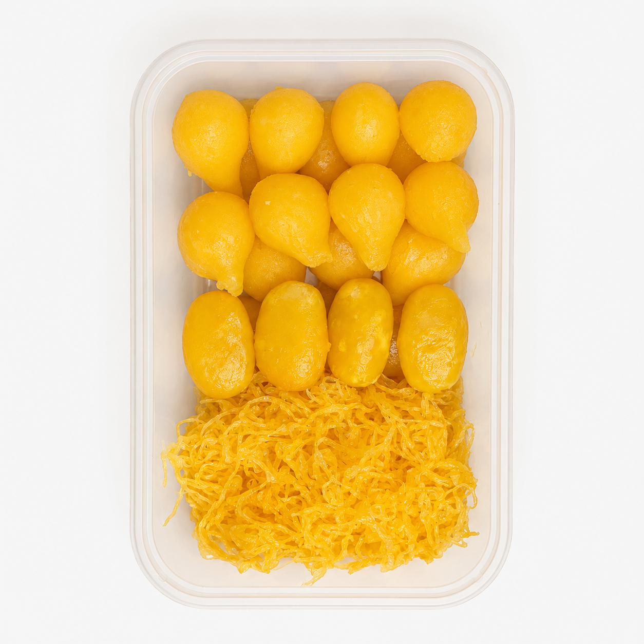 A clear plastic container holding bright yellow food items, with a shredded yellow topping on top and several glossy yellow oval pieces arranged below, photographed on a white background.