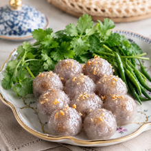 A plate of cooked meatballs garnished with chopped garlic, served with fresh cilantro and green beans on a decorative ceramic plate.